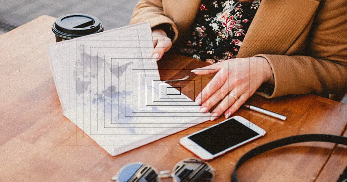A close-up view of a hand holding a pen and examining financial charts on paper. — Foto: Kindel Media / Pexels