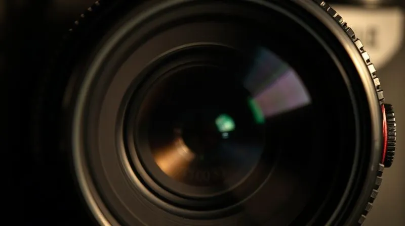 A close-up, photorealistic image of a vintage, high-value camera lens with a shadow of a question mark falling across it, cinematic lighting, sharp focus on the lens, depth of field blurring the background, 8K hyper-detailed. The lens reflects a subtle, worried expression.