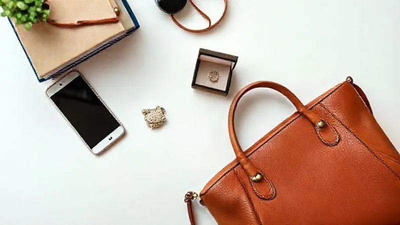 A photorealistic bird's-eye view of a neatly organized table with various items laid out for sale: a gently used smartphone, a stack of books, a small piece of jewelry, and a designer handbag. The scene is brightly lit, showcasing the items clearly against a clean, simple background. Shot on a high-end DSLR, 8K hyper-detailed, professional photography.