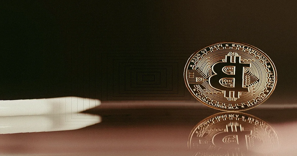 Closeup of Bitcoin coins with a market chart in the background showing financial trends. — Foto: DS stories / Pexels